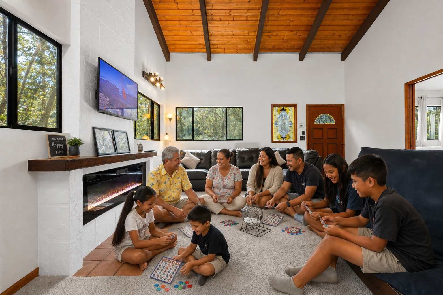 A family gathered around a table playing a board game in a living room with a fireplace, large windows, and a television.