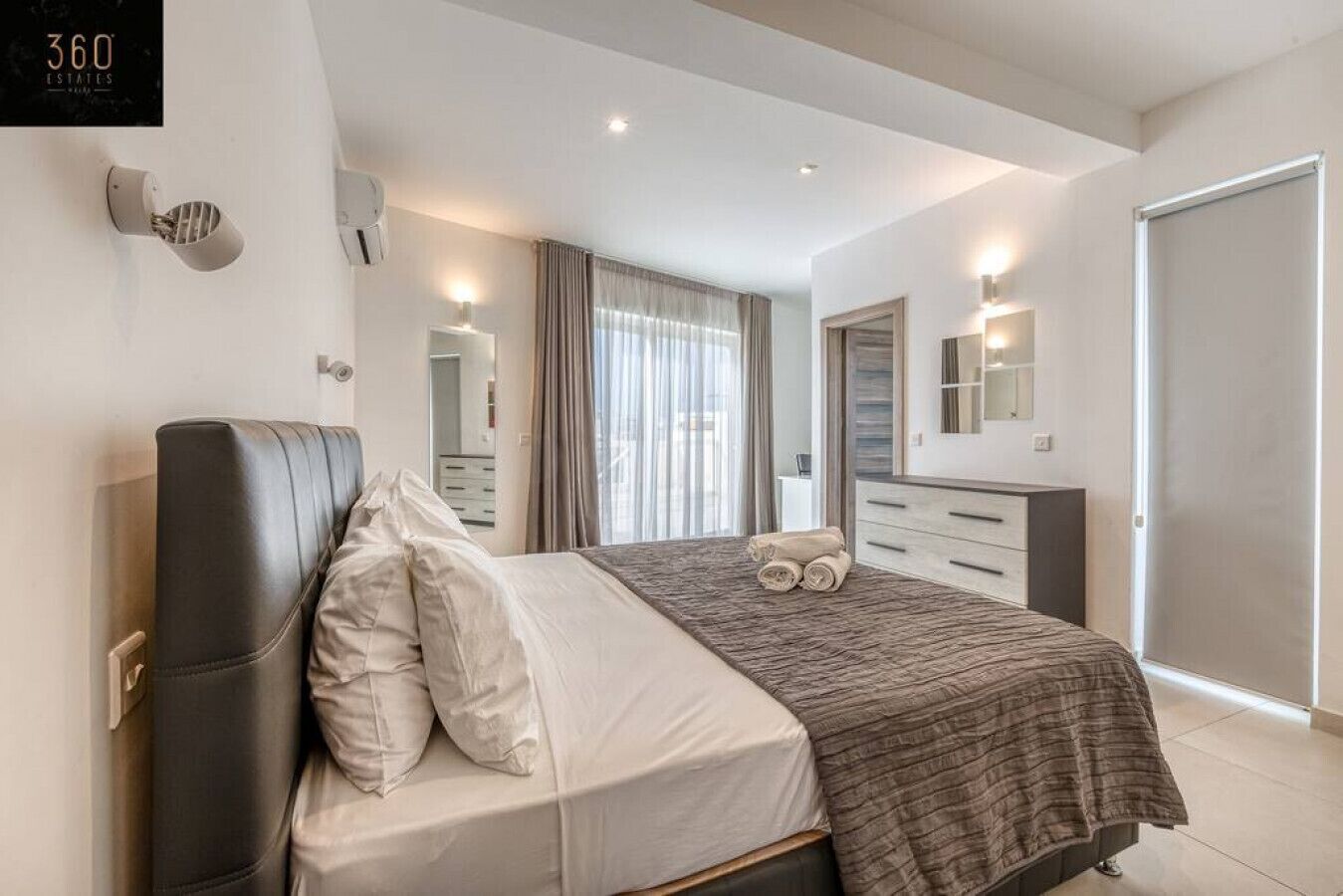 Ein modernes Schlafzimmer mit Bett, Nachttisch, Spiegel und Kleiderschrank.