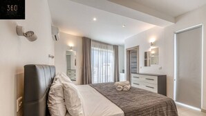 Un dormitorio moderno con una cama, una mesita de noche, un espejo y un armario.