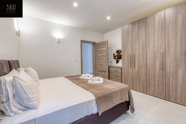 A modern bedroom with a large bed, a wardrobe, and a door.