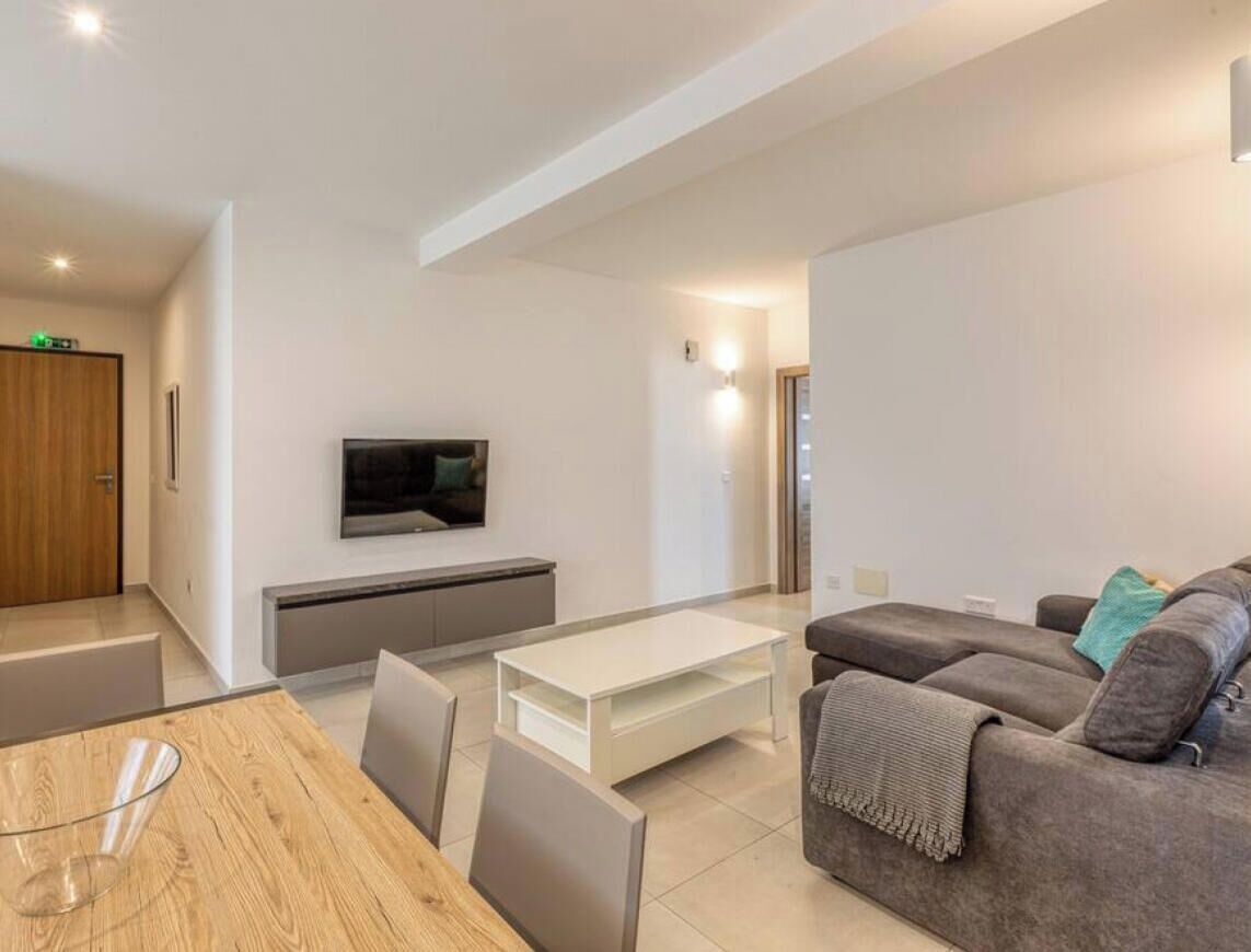 A modern living room with a TV, sofa, and dining area.