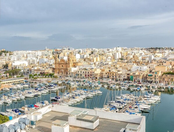 A marina filled with boats, a cityscape with historic buildings, and a clear sky.