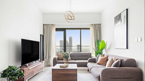 A modern living room with a flat-screen TV, a wooden coffee table, a grey sofa, and a large window with a city view. - Silkhaus Burj Royale, Downtown Dubai (Dubai)