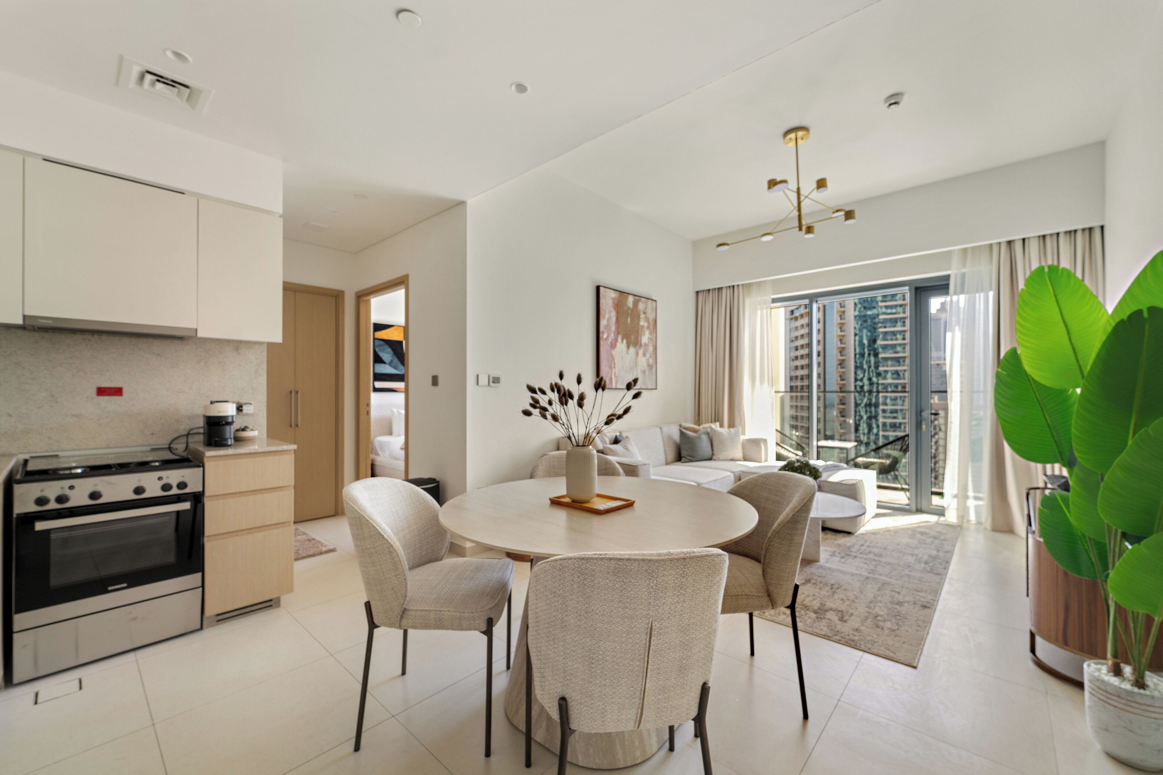 Eine moderne Küche mit Backofen, eine Essecke mit rundem Tisch und Stühlen sowie ein großes Fenster mit Blick auf die Stadt.