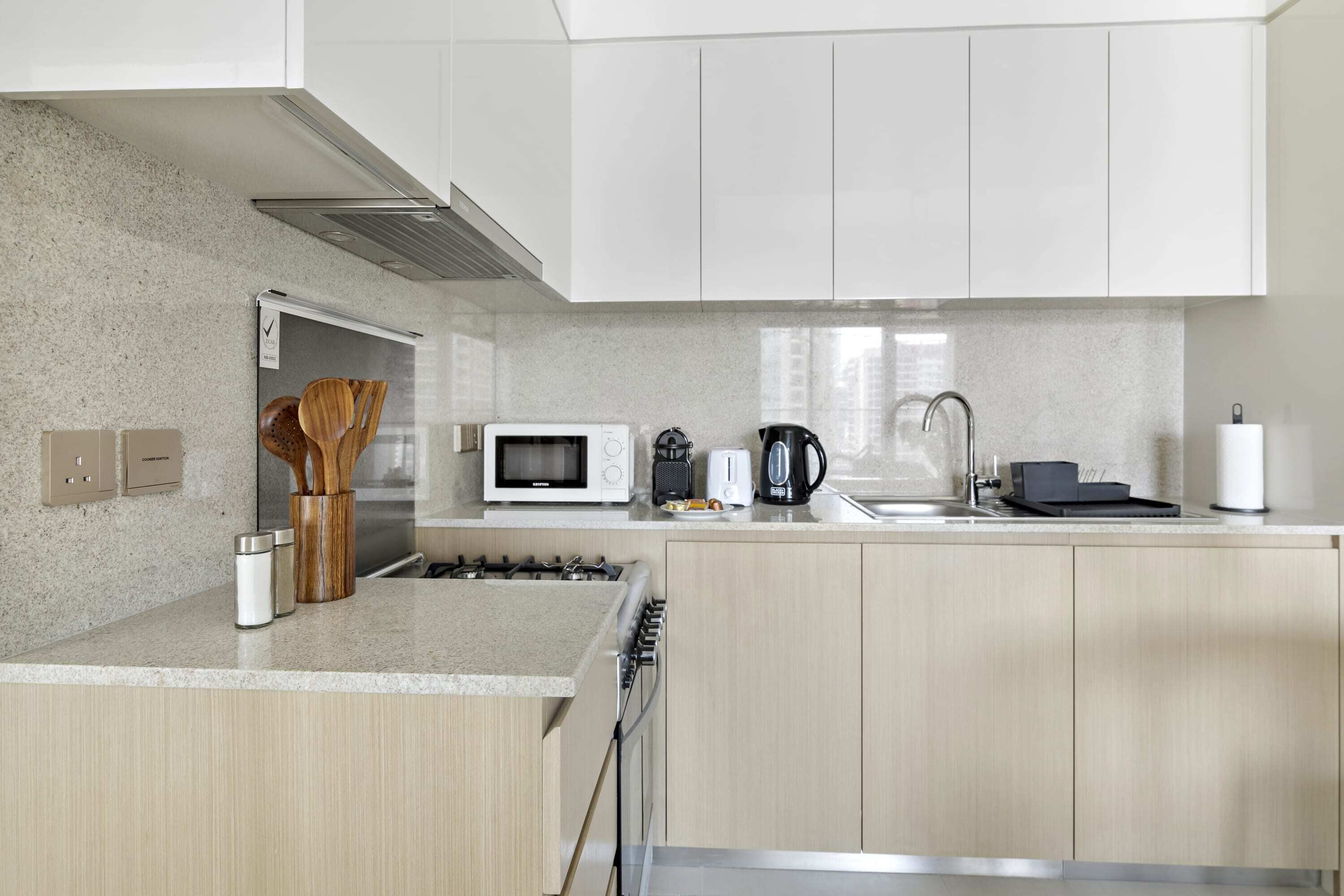 A modern kitchen with white cabinets, a microwave, a coffee maker, and a gas stove.