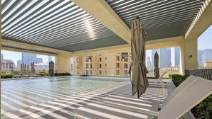 A rooftop pool area with lounge chairs and umbrellas, large windows offering city views. - Silkhaus Burj Royale, Downtown Dubai (Dubai)