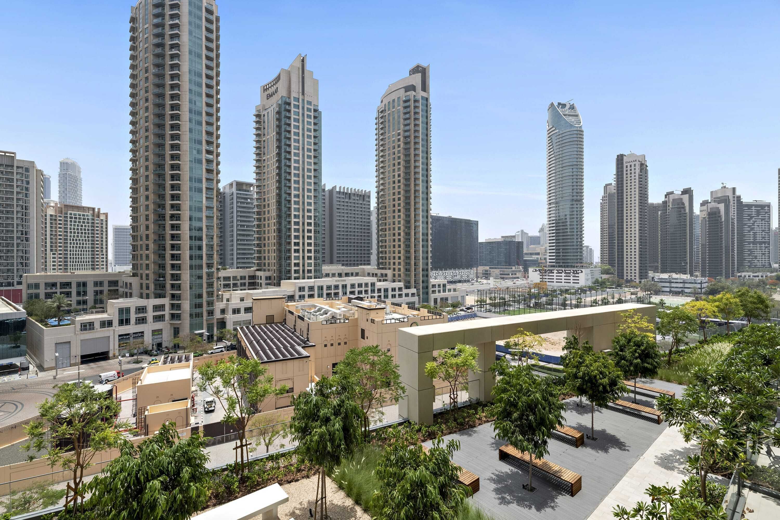 A high-rise urban area with modern buildings, a rooftop garden, and a parking area.