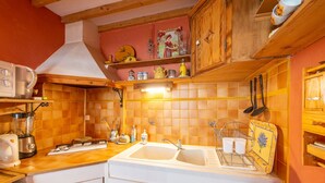 Une cuisine équipée d’un évier à deux bacs, de meubles en bois, d’un four à micro-ondes et d’un mixeur.