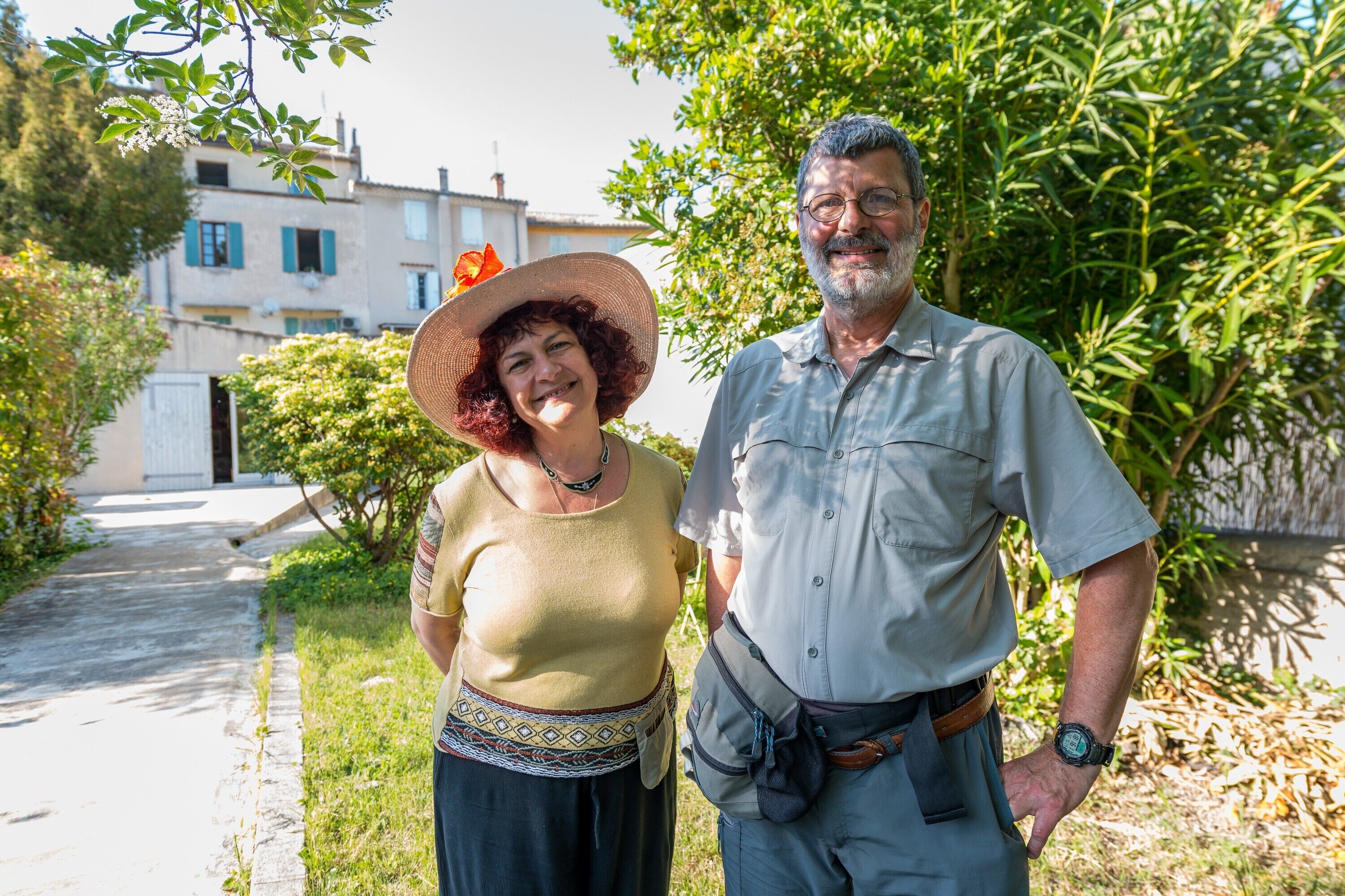 A man and a woman standing outdoors with a building in the background.