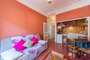 A compact living space with a sofa, dining table, and kitchenette. - Le Pontias - Ambiance Art Déco (Nyons)