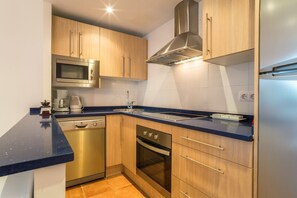 A modern kitchen with stainless steel appliances, wooden cabinets, and a blue countertop.