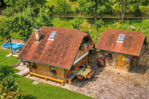 Two wooden cabins with sloped roofs, stone foundations, and outdoor seating areas. - Rudnica Hill Lodge With Private Garden (Podcetrtek)