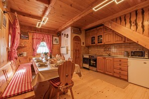 A wooden cabin interior with a dining table set for four, wooden cabinets, a kitchen area, and a staircase. - Rudnica Hill Lodge With Private Garden (Podcetrtek)