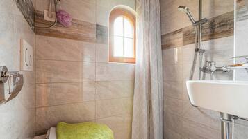 Un baño con ducha, lavabo, ventana y toallero.