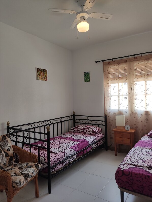 A bedroom with a single bed, a chair, a nightstand with a clock, and a ceiling fan. - Confort Apartamento con Excelentes Vistas al mar (VC)