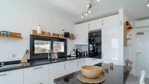A modern kitchen with white cabinets, a black countertop, and a wooden bowl centerpiece. - Villa Luxuria Private Pool by Casasol (Nerja)
