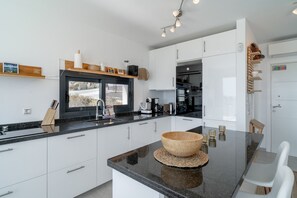 Eine moderne Küche mit weißen Schränken, einer schwarzen Arbeitsplatte und einer Holzkulisse in der Mitte.