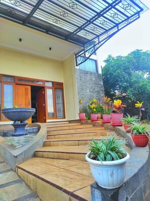 A building entrance with a covered porch, steps leading up to the door, and potted plants. - Homestay Semarang  (Semarang)