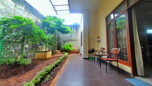Un espace extérieur abrité, doté d’un chemin pavé, de plantes en pot et d’un coin salon avec des chaises et une table.