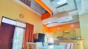 Une cuisine moderne avec un coin repas, comprenant une table et des chaises en verre, un îlot de cuisine et une horloge visible au mur.