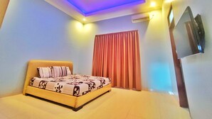 Une chambre à coucher avec un lit, des rideaux, un téléviseur fixé au mur et un appareil de climatisation.