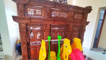 Zona de juegos con tobogán y columpios frente a una pared con intrincados grabados.
