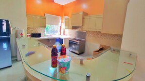 Une cuisine moderne dotée d’un îlot central en verre, d’appareils électroménagers en acier inoxydable et de murs orange.