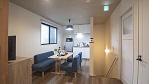 A compact living space with a kitchenette, a dining area with a table and chairs, and a sofa. - TokinoyadoNijo (Kyoto)