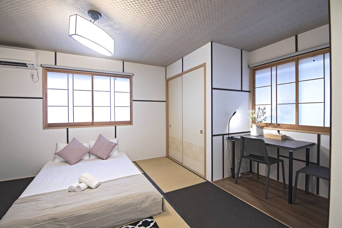 Una habitación con cama, escritorio y ventana.