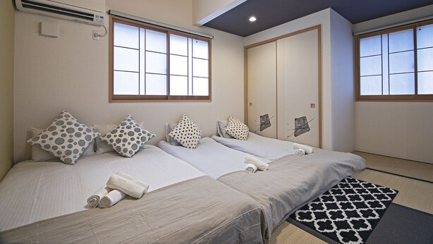A hotel room with two beds, a large window, an air conditioning unit, and a traditional Japanese sliding door. - TokinoyadoNijo (Kyoto)