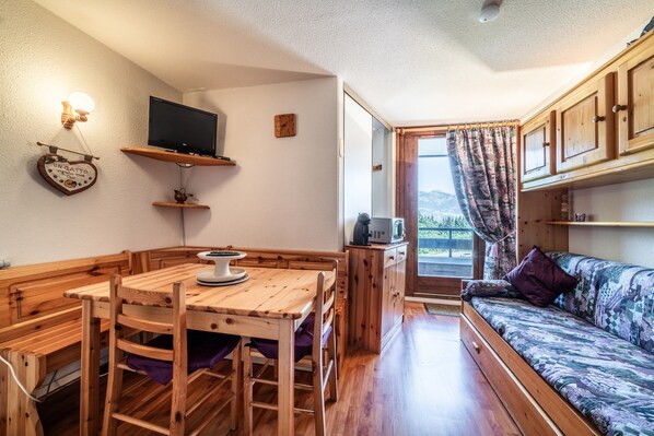 A cozy room with a wooden dining table, chairs, a sofa, a television, and a window with a view. - Apartment 'Nikye Morillon 5 Personnes' with Mountain View and Balcony (Morillon)