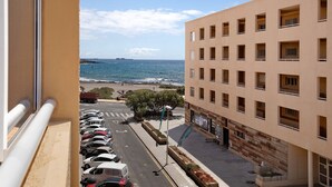 A building with multiple balconies overlooking a beach, a parking lot with cars, and a clear view of the sea. - Medano Beach Home Ocean View Apartment with Sea Views, Balcony and Wi-Fi (El Medano)