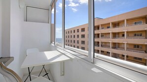 A balcony with a table and chairs, a view of a building, and a clear sky. - Medano Beach Home Ocean View Apartment with Sea Views, Balcony and Wi-Fi (El Medano)