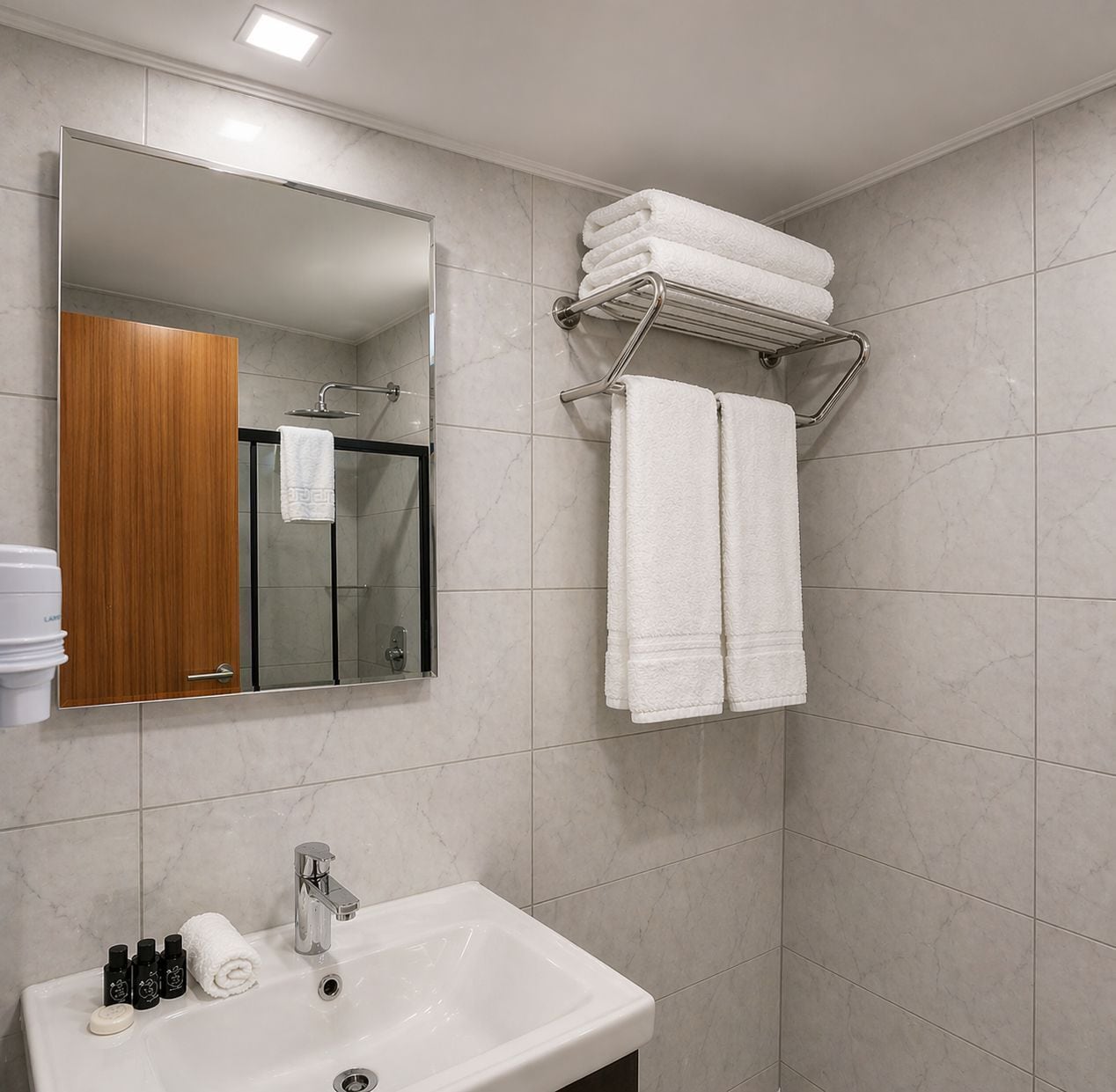 A bathroom with a sink, mirror, towel rack, and shower.