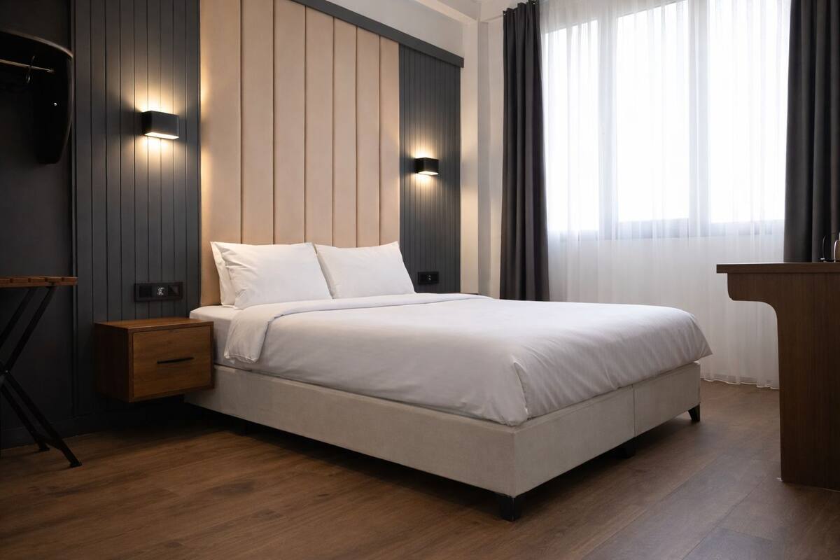 Une chambre à coucher moderne avec un lit, des tables de chevet et un bureau.