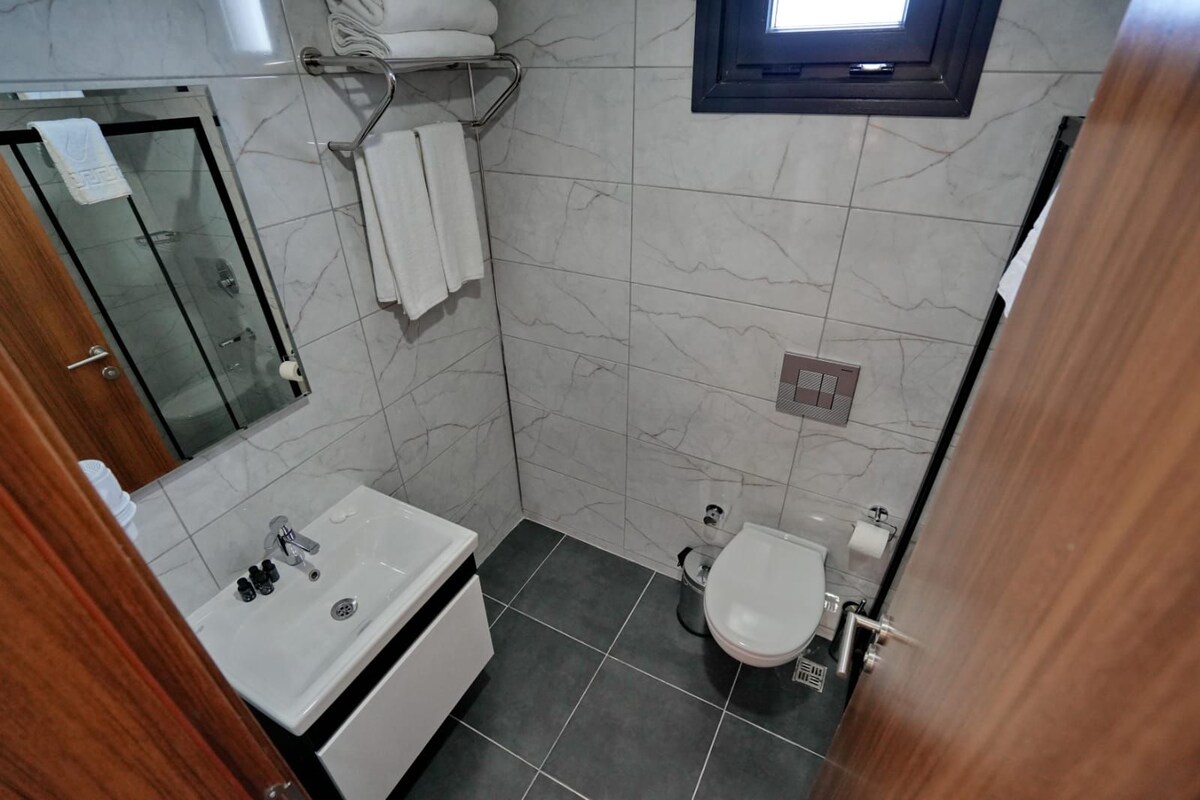 Une salle de bain équipée d’un lavabo, de toilettes et d’un porte-serviettes.