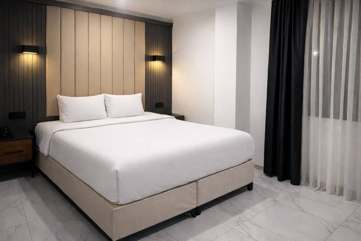 Une chambre moderne avec un grand lit, deux tables de chevet et des lampes fixées au mur.