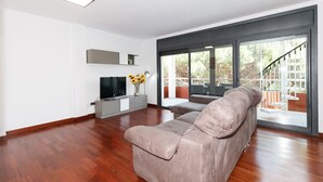 Een moderne woonkamer met een groot raam, een flatscreen televisie en een bank.