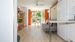 Una cocina moderna con armarios blancos, un sofá gris y un comedor con mesa y sillas.