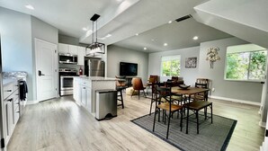 A modern kitchen with a dining area, featuring a large island, built-in appliances, and a view of the outdoors. - 3 Bedroom Townhome Suite (Ogden)