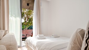 Un dormitorio con cama, una silla y vistas al exterior.