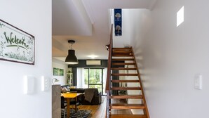 A modern interior with a wooden staircase leading to a dining area. - At Forest Stay | Apartment in Margaret River | New Listing (Margaret River)