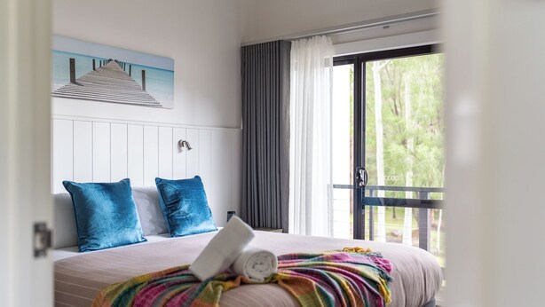 A bedroom with a bed, a window with curtains, and a view of greenery outside. - At Forest Stay | Apartment in Margaret River | New Listing (Margaret River)