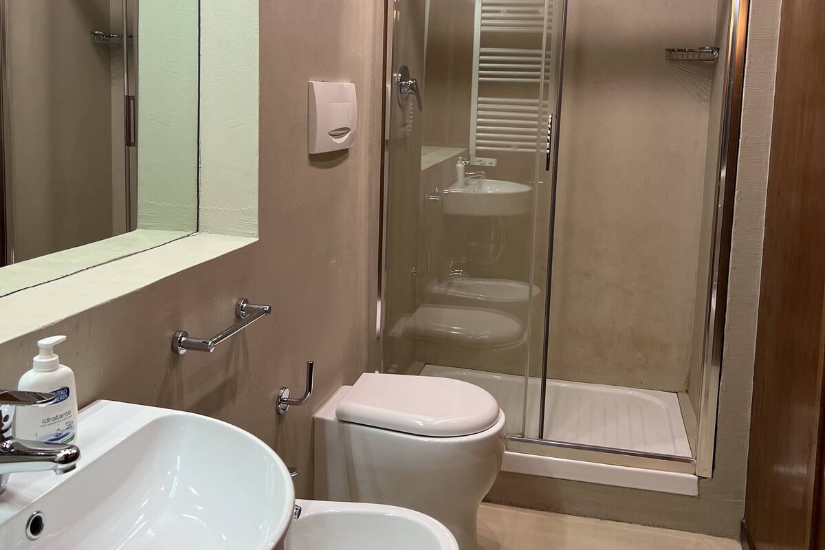 Une salle de bain moderne avec un grand miroir, un lavabo, des toilettes et une douche à parois de verre.