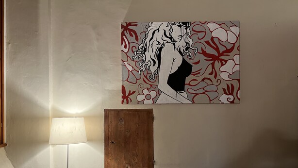 Une pièce avec une porte en bois, un mur blanc, une lampe et un canapé agrémenté de coussins à motifs.