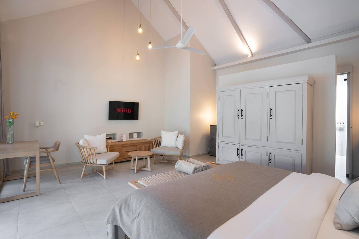 A modern bedroom with a bed, a desk, a chair, and a TV.