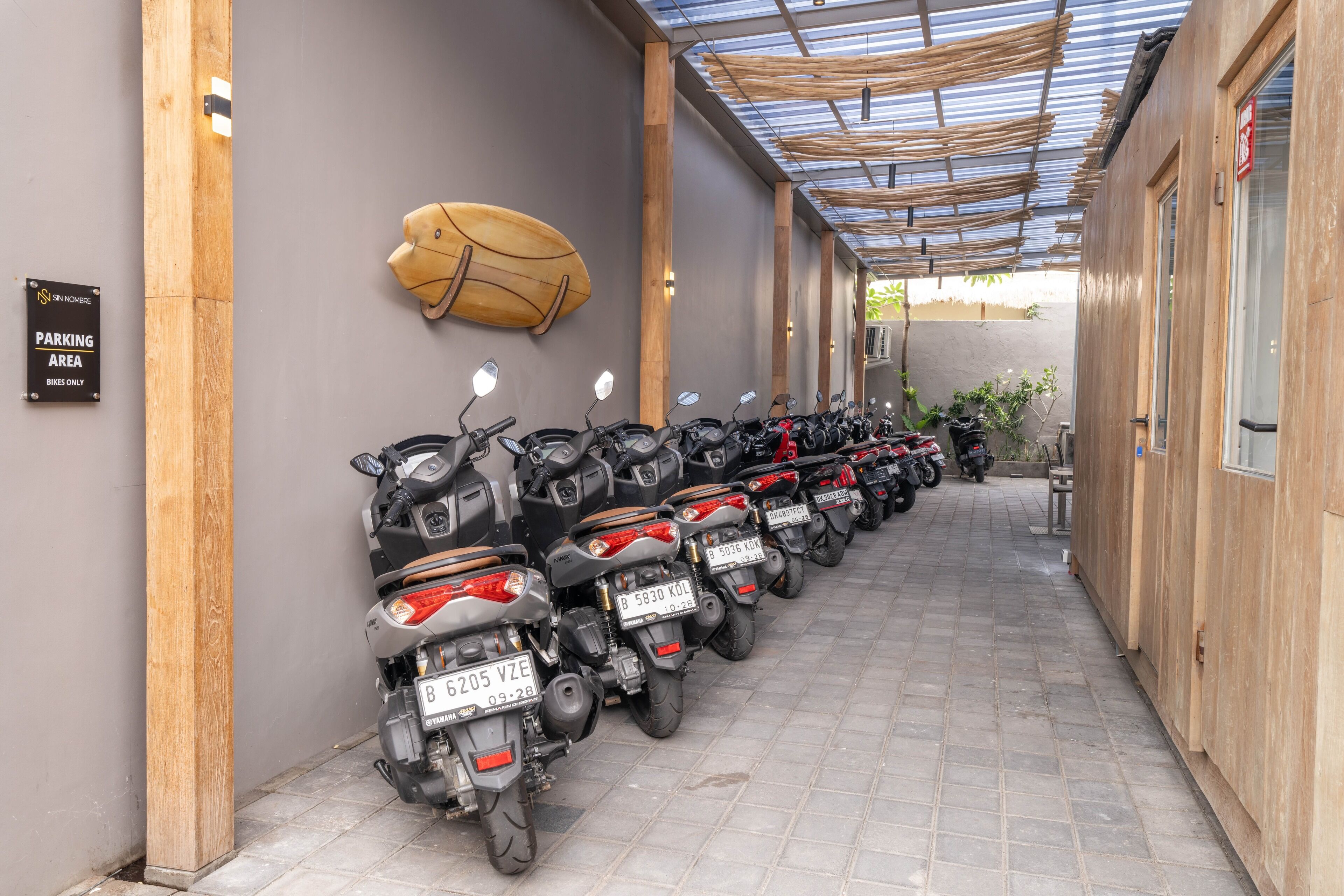 A row of motorcycles parked in a covered area with a sign indicating it is a parking area for bikes only.