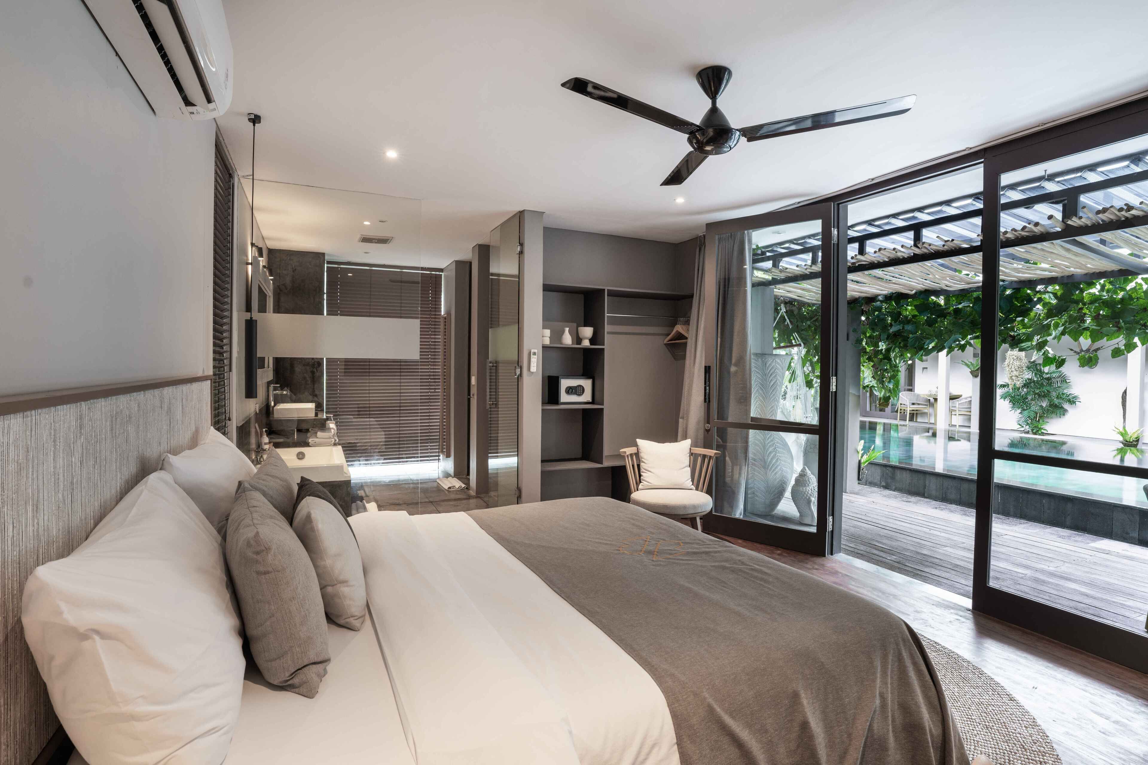Camera da letto moderna con un letto grande, una ventola a soffitto e vista su una piscina all'aperto.