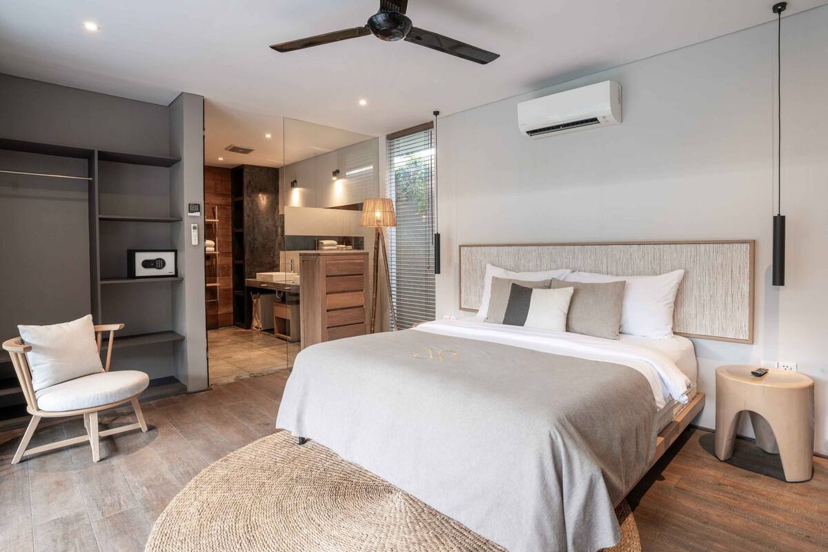 A modern bedroom with a large bed, a chair, a desk, and a wardrobe.