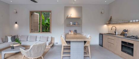 Una cocina moderna con comedor, ventilador de techo y un ventanal con contraventanas.